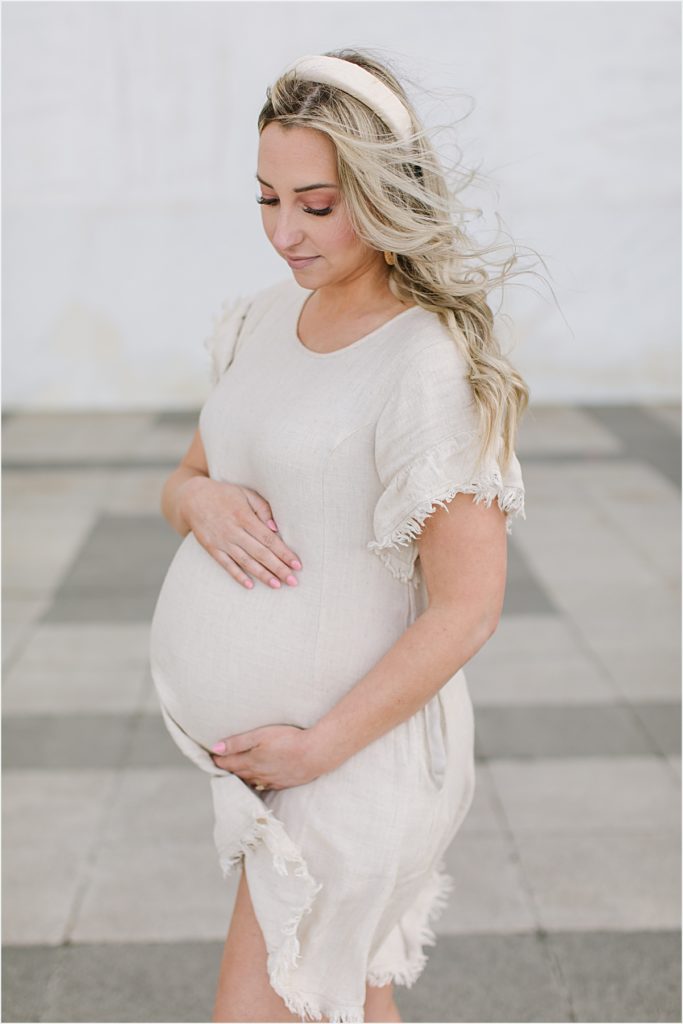 Pregnant woman holding belly and looking down at belly for maternity session