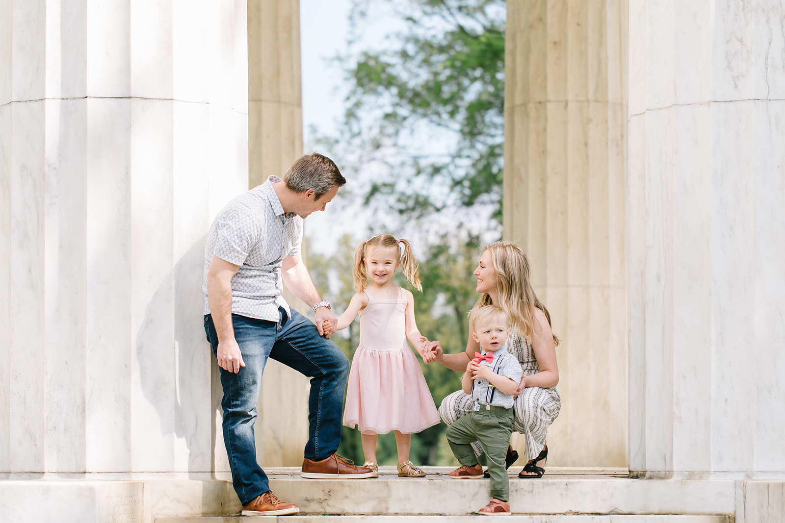 Mom and dad with their son and daughter laughing near columns