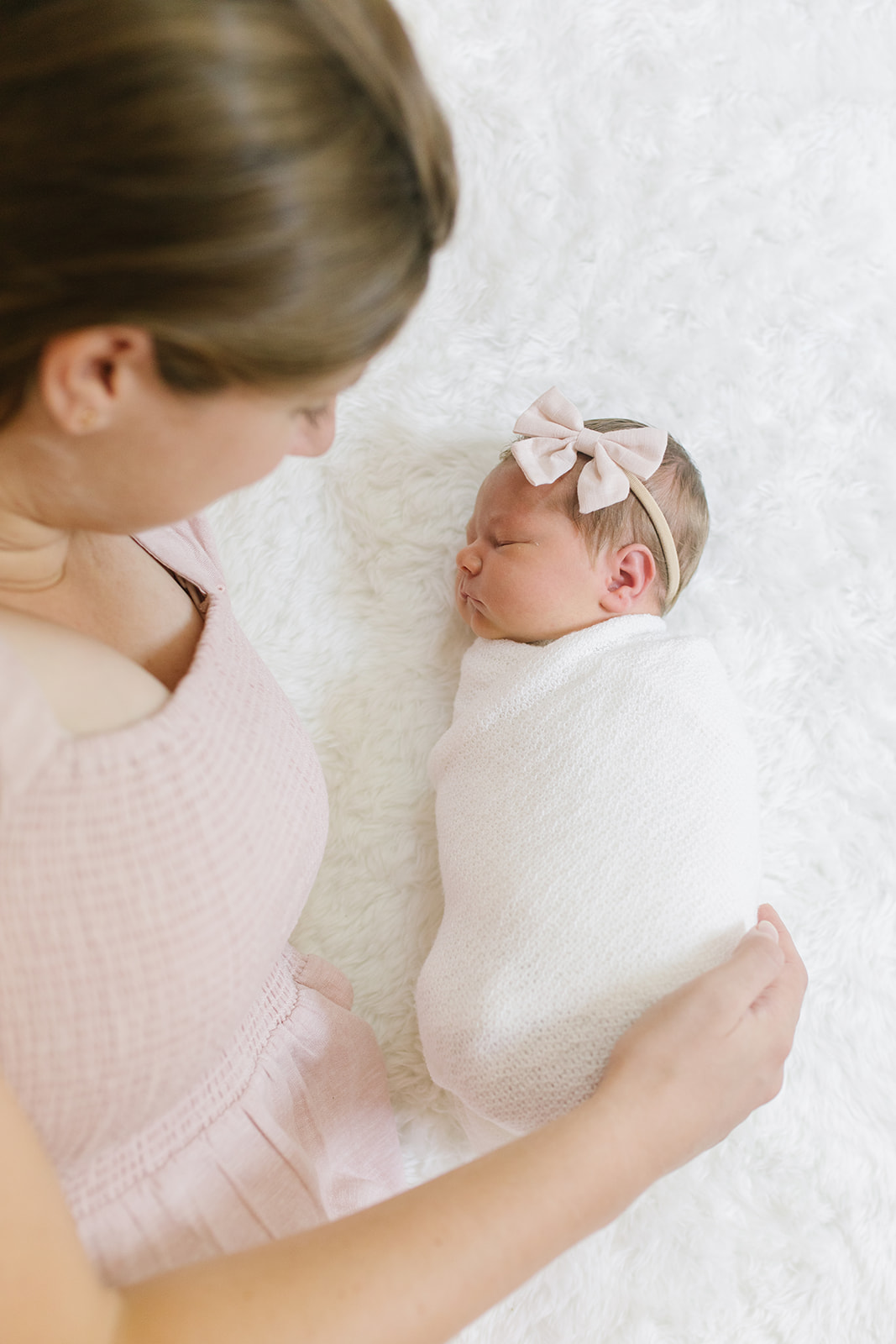 mom looking at newborn girl in white wrap