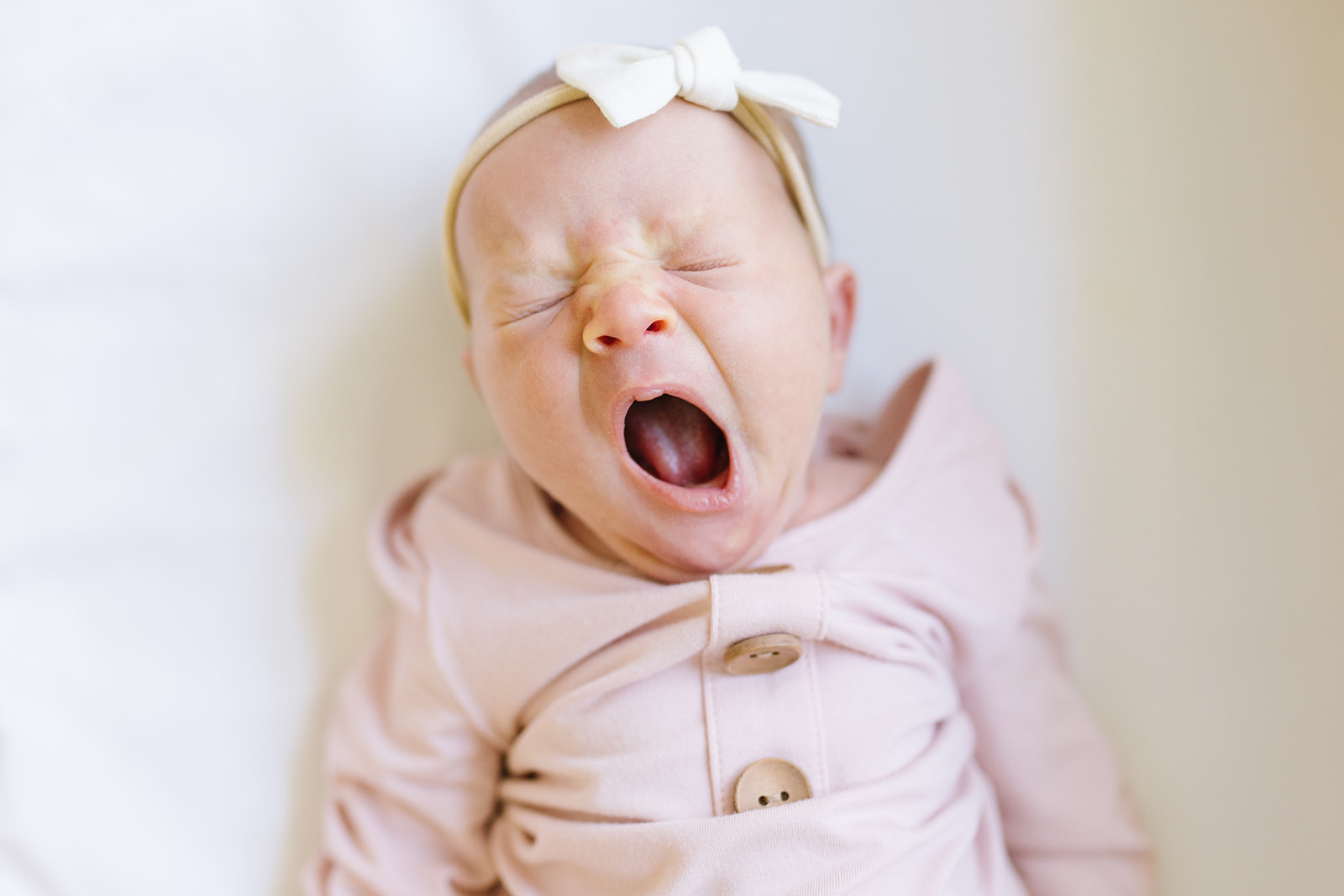newborn baby girl in a white bow yawning Northern Virginia Newborn Photographer