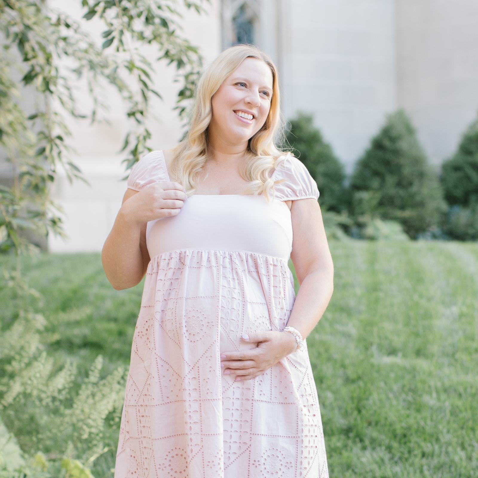 pregnant woman in pink dress holding her bump in greenery Maternity Photography DC