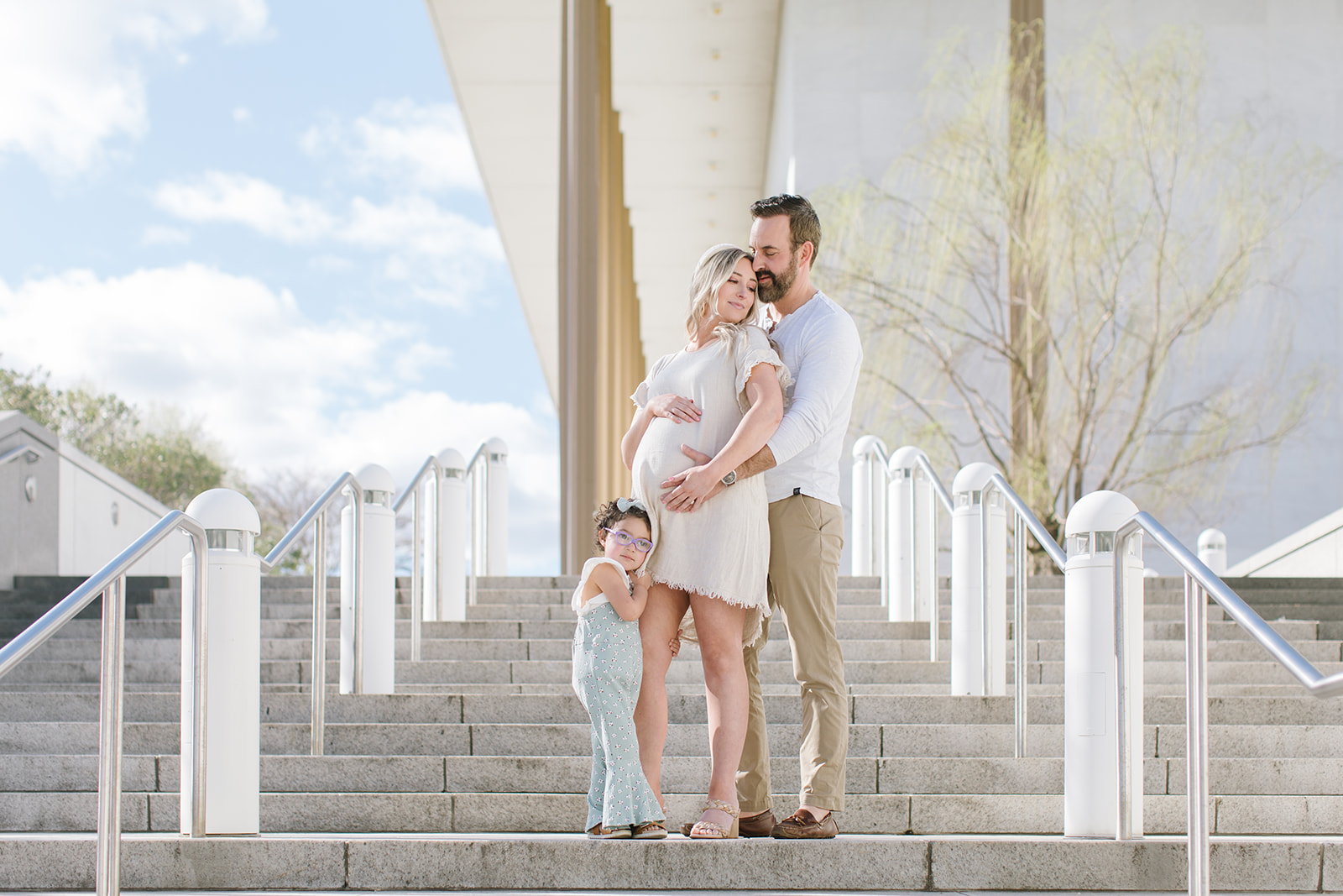 mom to be with her husband and daughter all holding her bump on a set of stairs Maternity Photography DC