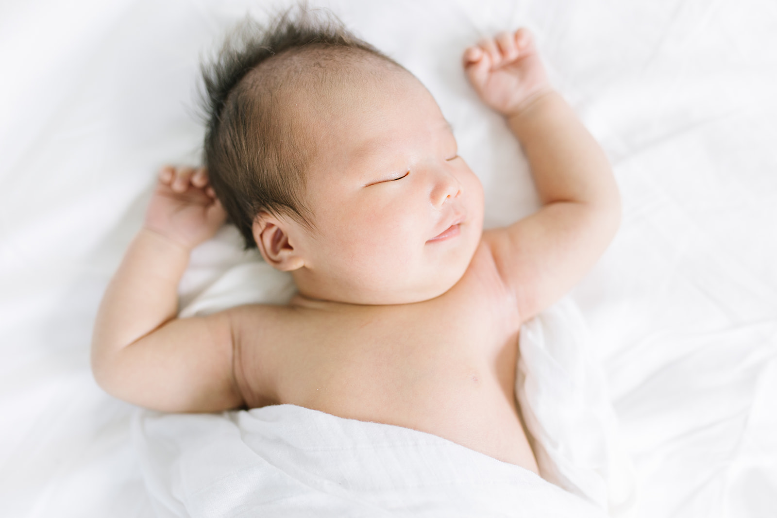 newborn baby stretching their arms up on a bed Washington DC Baby Photographer