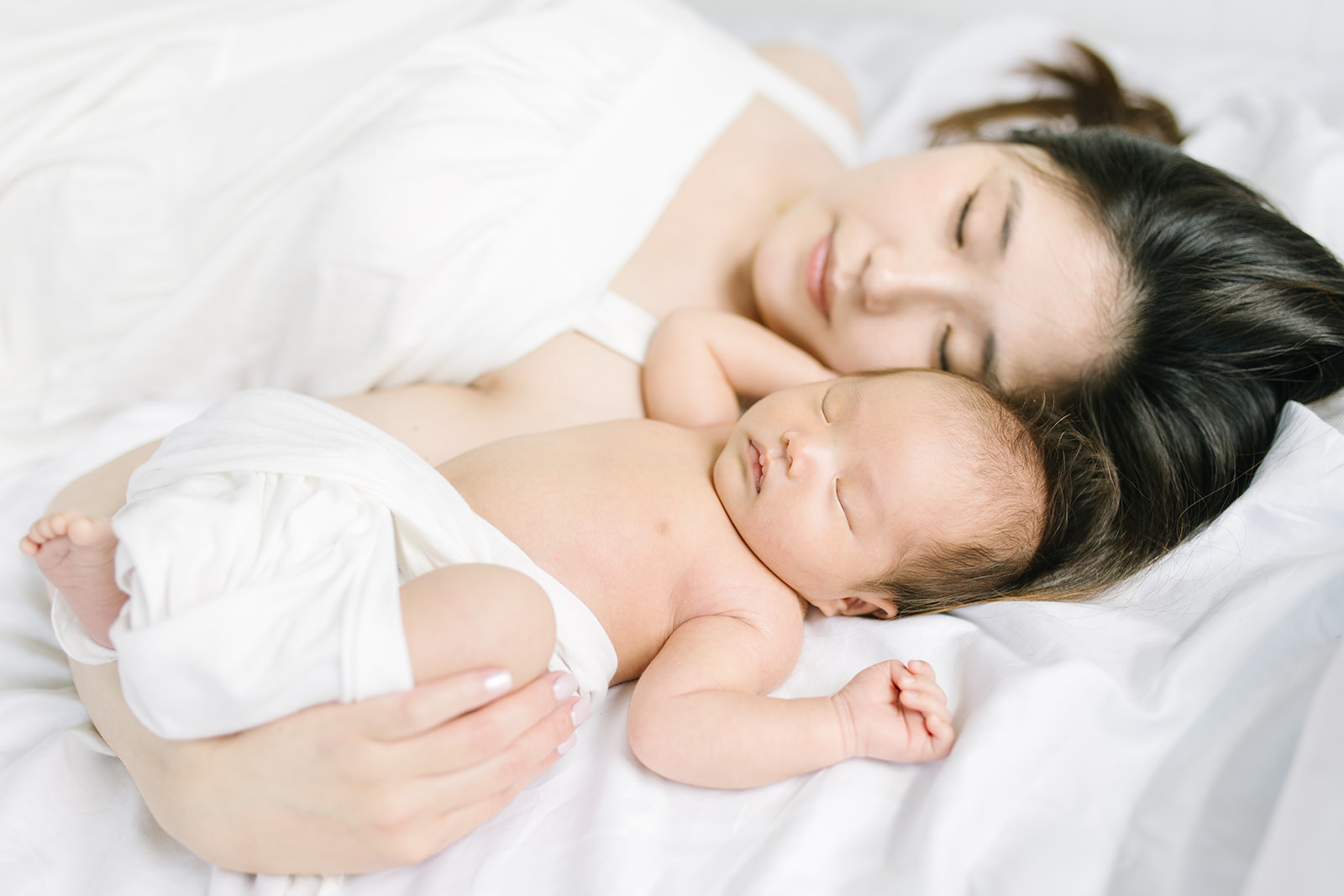 mom and newborn baby snuggling on a bed Washington DC Baby Photographer