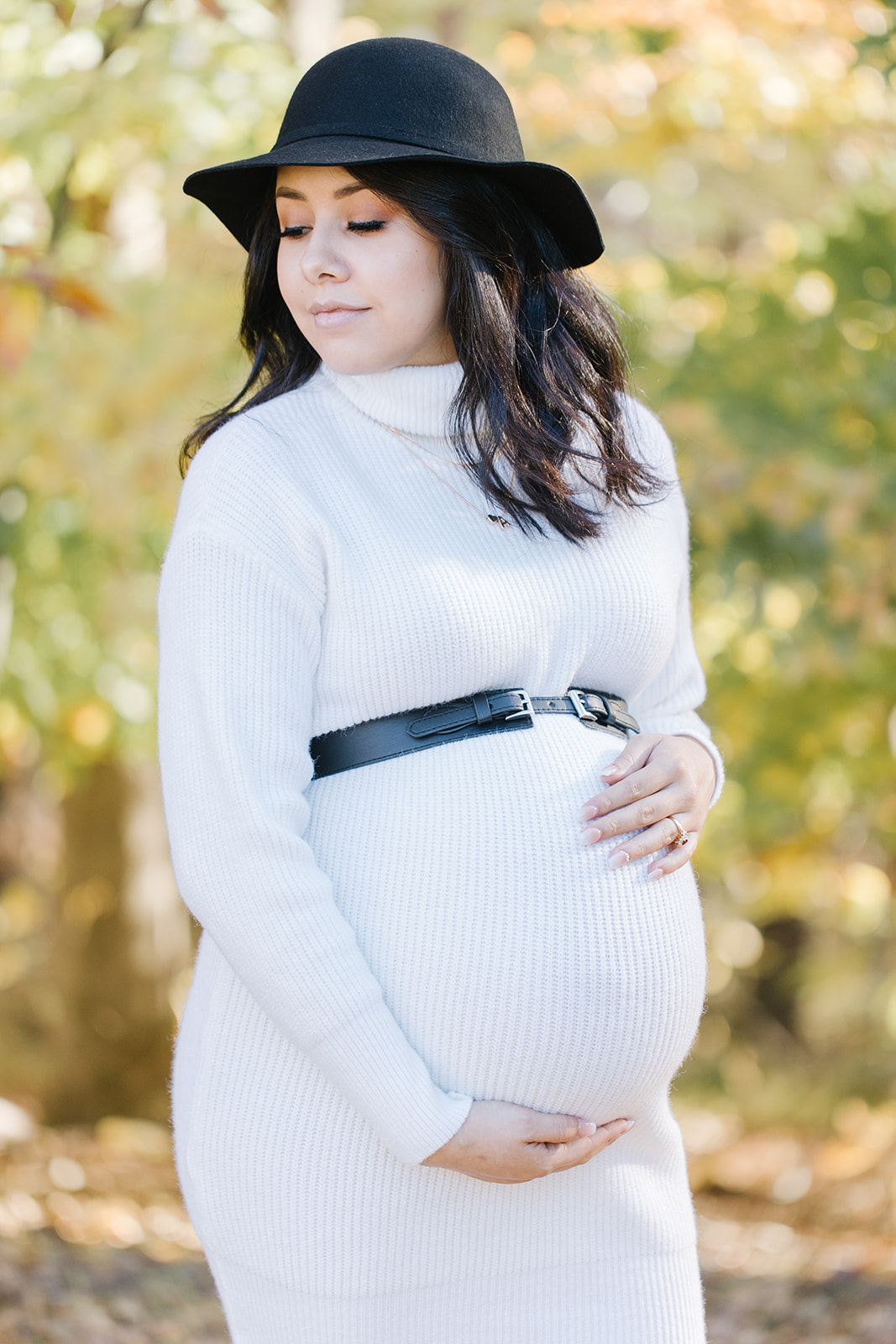 mom to be in a white maternity gown and belt holding her bump Bloom OBGYN