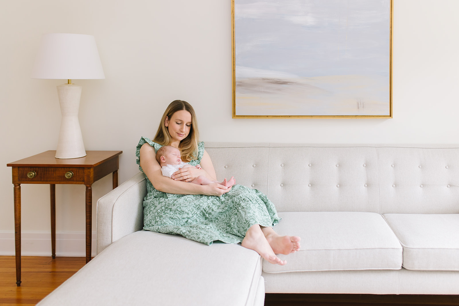 mother relaxes with her newborn on her lap on a modern style couch interior design washington dc