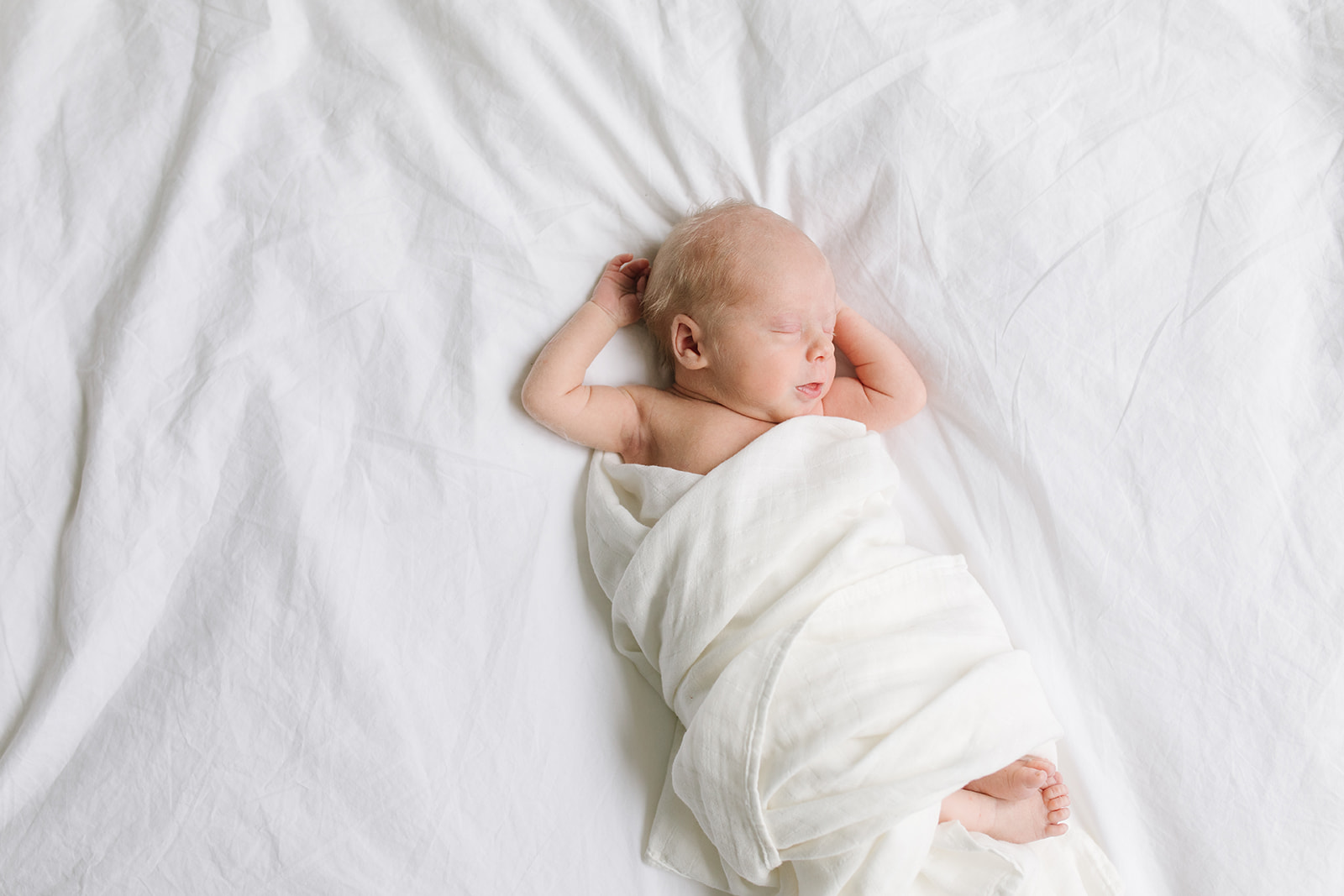 newborn baby sleeps in a white bed with arms behind its head infant cpr washington dc
